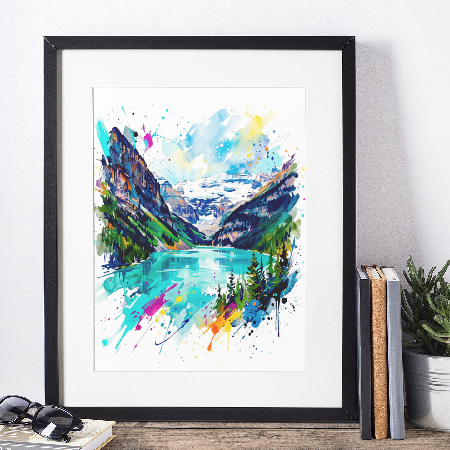 A framed watercolor art print of a Lake Louise, Alberta, styled on a wooden shelf next to books, sunglasses, and a potted plant.
